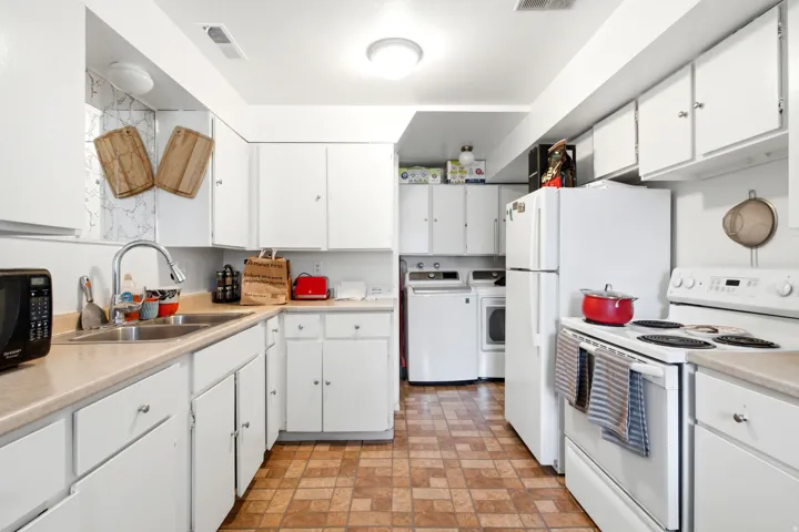 Kitchen featuring white cabinetry, light-toned countertops, a stainless steel sink, and patterned floor tiles