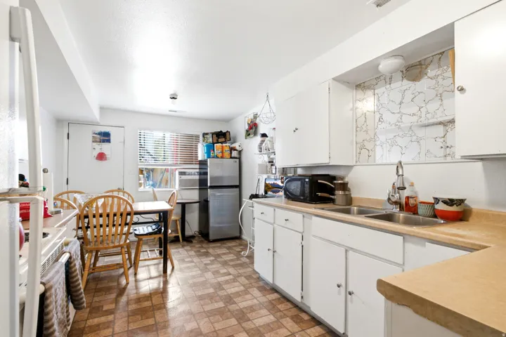 Kitchen featuring white cabinetry, a double basin stainless steel sink, laminate countertops, and patterned vinyl flooring