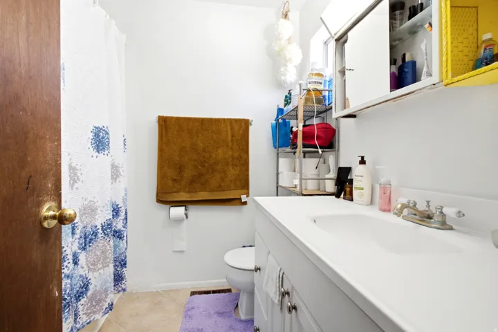 Bathroom featuring a white vanity with an integrated sink, chrome faucet, and white cabinetry with brushed nickel hardware