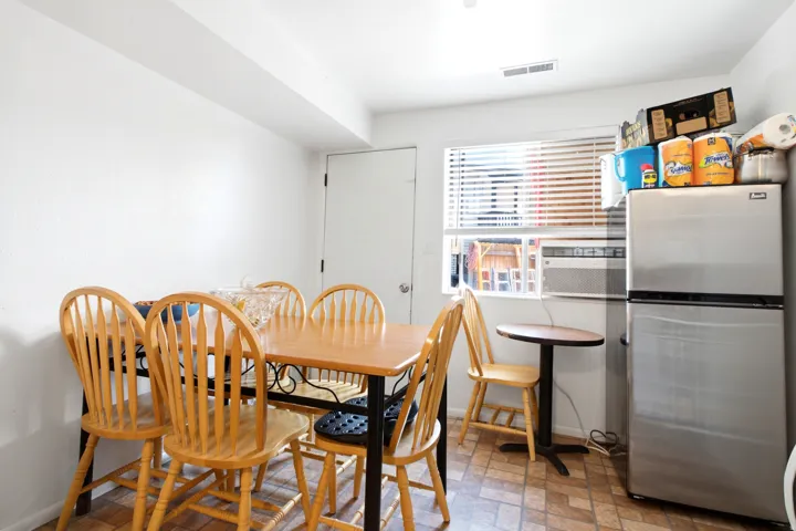 Kitchen area featuring patterned floor tiles, white painted walls, a window with horizontal blinds, and a built-in air conditioning unit