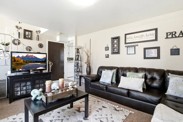 Carpeted living area with light-toned walls, a dark wood media console, and a dark wood coffee table