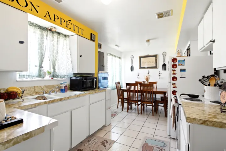 Kitchen featuring white cabinetry, light-toned countertops, a double-basin sink, and tile flooring