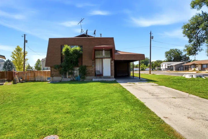 Front exterior featuring a brown shingle roof, brick lower facade, covered entry, and an integrated carport