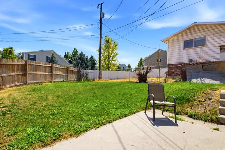 Expansive backyard featuring a concrete patio, a substantial wood privacy fence, and a chain-link fence