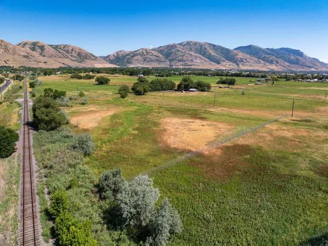 Expansive agricultural land featuring a chain-link fence and railroad tracks