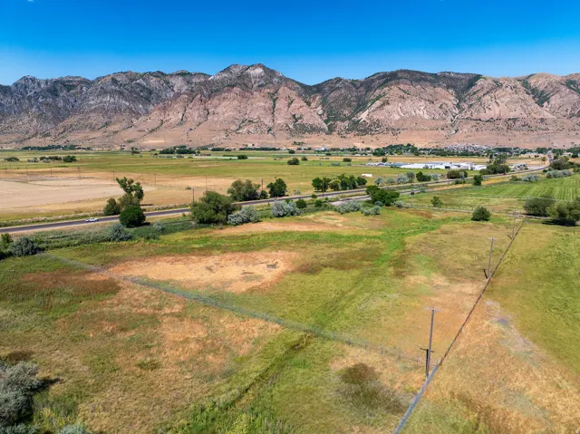 Expansive open land with varied vegetation, bordered by a road