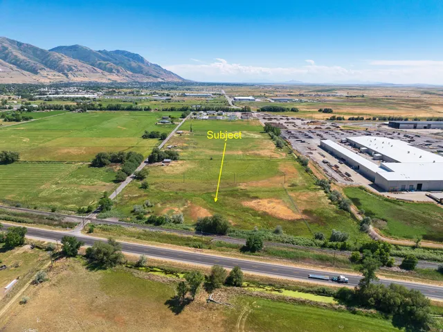 Expansive land parcel featuring open fields, existing roadways, and surrounding commercial structures