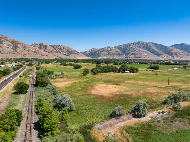 Expansive rural landscape featuring a roadway, railroad tracks, and natural vegetation