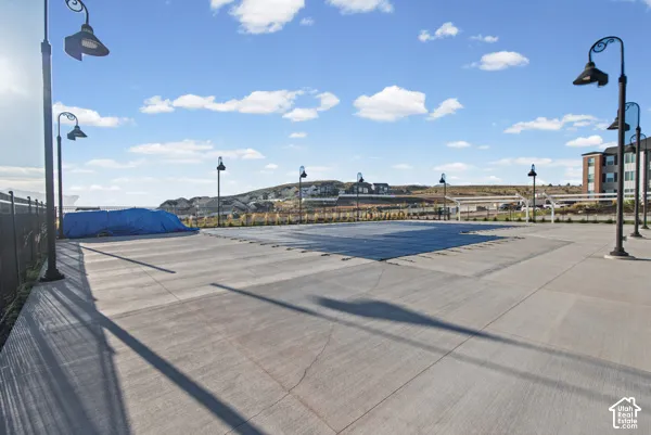 Expansive concrete patio area with multiple decorative lampposts and a fenced perimeter