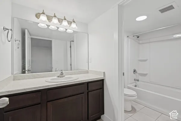 Spa-inspired primary bathroom featuring a dark wood vanity with dual sinks, marble-look countertop, and an oversized framed mirror with integrated lighting