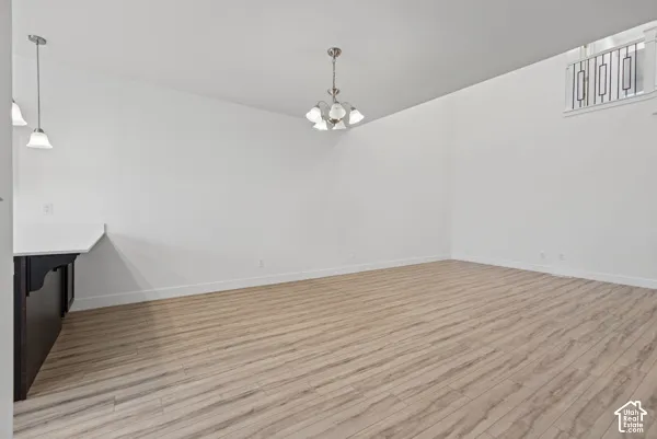Light wood-finish flooring, white walls, and a multi-light chandelier