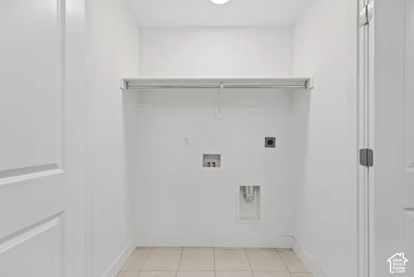 Recessed laundry area featuring tile flooring, a hanging rod, and wall-mounted utility connections