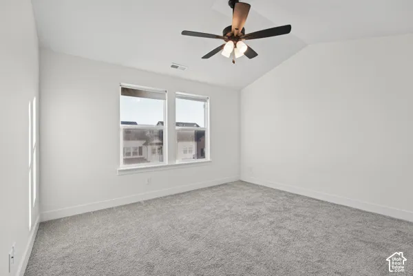 Bright bedroom featuring expansive windows with natural light, neutral wall finishes, soft carpet flooring, and a ceiling fan with integrated lighting