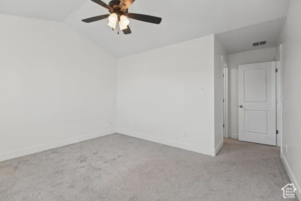 Vaulted ceiling with a ceiling fan, light gray carpet, white walls, and a white interior door with a silver-tone knob