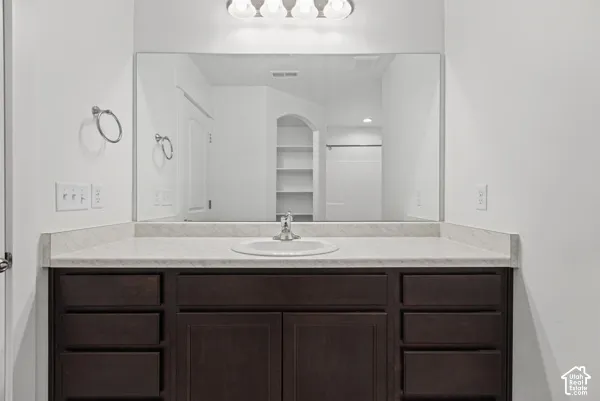 Dark wood-finish vanity with a single basin sink, laminate countertop, and full-width mirror