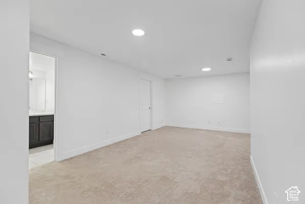 Neutral tone carpeting, recessed lighting, and a white interior door
