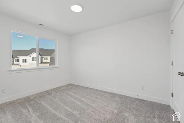 Neutral-toned carpeting, white walls, and a large window with white trim