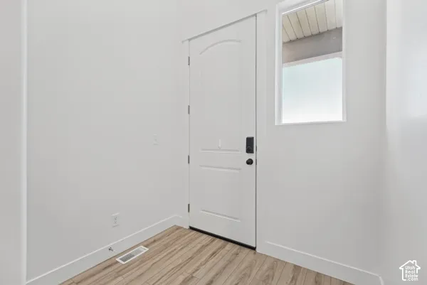 White interior door with black hardware, wood-finish flooring, white walls, and a transom window