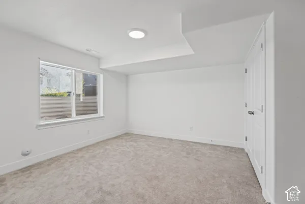 Bright, light-filled bedroom featuring neutral carpeting, recessed ceiling lighting, and a large window with horizontal blinds