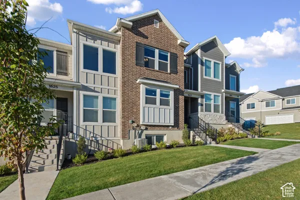 Brick and siding exterior with multiple window styles, concrete sidewalks, and established landscaping