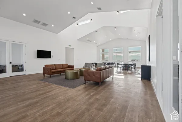Expansive open-concept living space featuring soaring vaulted ceilings with skylights, abundant natural light from multiple large windows, and wide-plank wood-finish flooring throughout