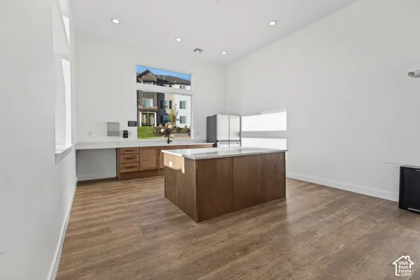 Kitchen featuring wood-finish flooring, an expansive island with a light-toned countertop, and recessed lighting
