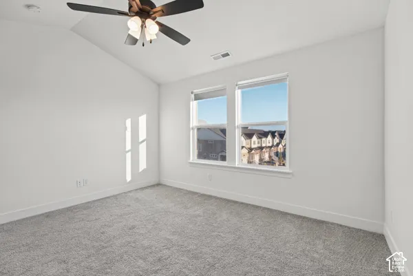 Vaulted ceiling, ceiling fan with integrated lighting, dual pane windows, and gray carpet flooring