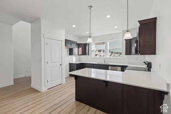 Kitchen featuring wood-finish flooring, dark wood cabinetry, light-toned countertops, and recessed lighting