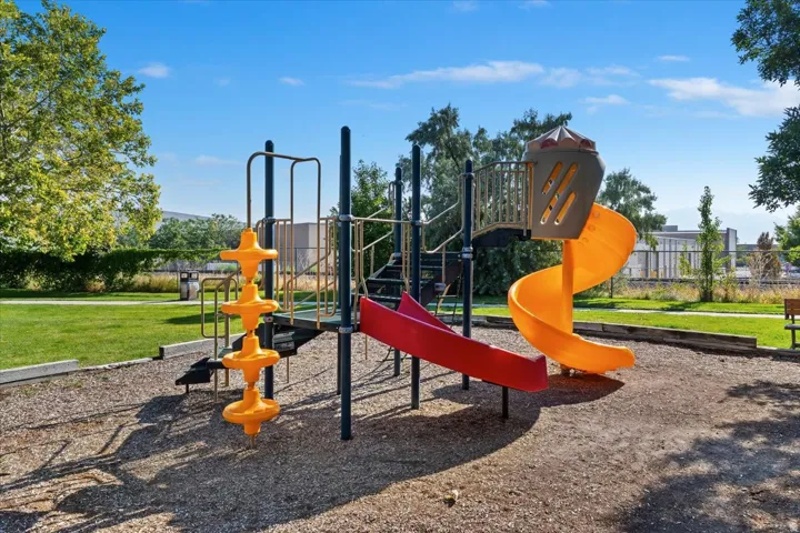 Recreational playground structure featuring vibrant orange spiral slide, red straight slide, and a climbing element