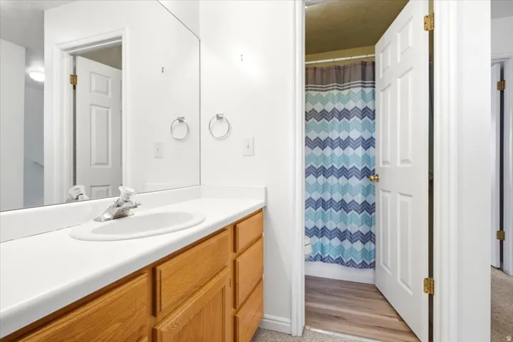 Bathroom vanity featuring a light wood-finish cabinet with multiple drawers, a white countertop, and an integrated oval sink with a chrome faucet