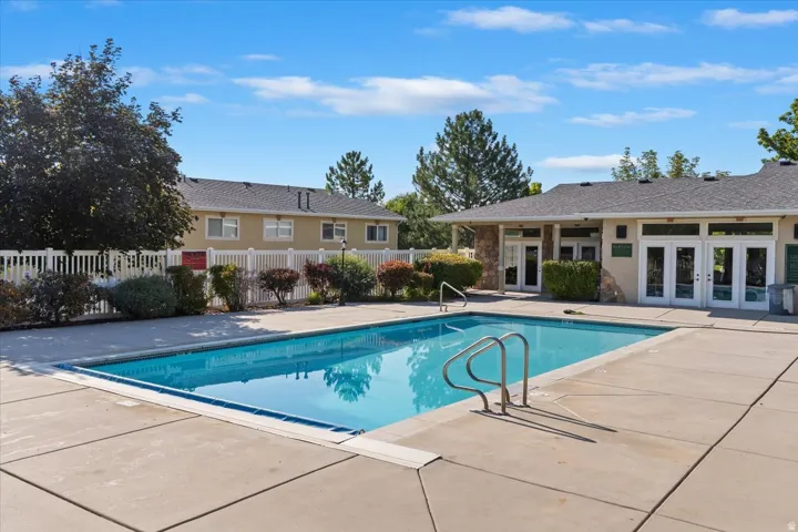 Outdoor swimming pool surrounded by concrete decking and lush landscaping