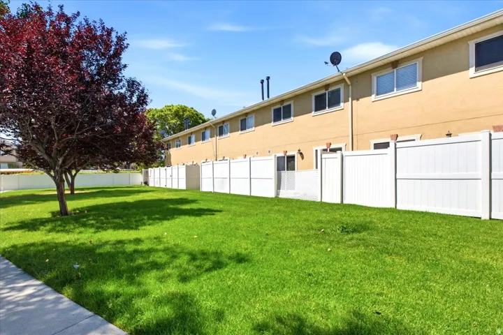 Expansive green lawn area featuring mature deciduous trees and a full privacy fence