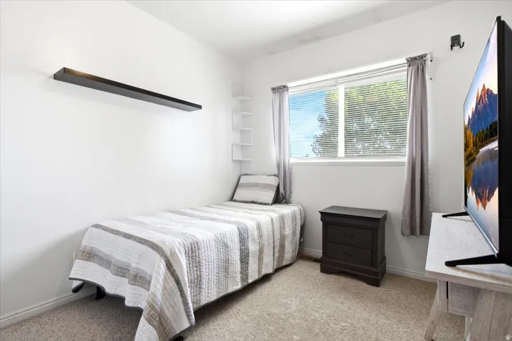 Bright room featuring neutral carpeting, a white floating shelf, and a double-hung window with blinds