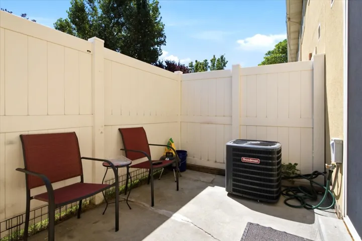 Private outdoor patio space featuring concrete flooring, a neutral-toned privacy fence, exterior wall with stucco finish, and an outdoor HVAC unit