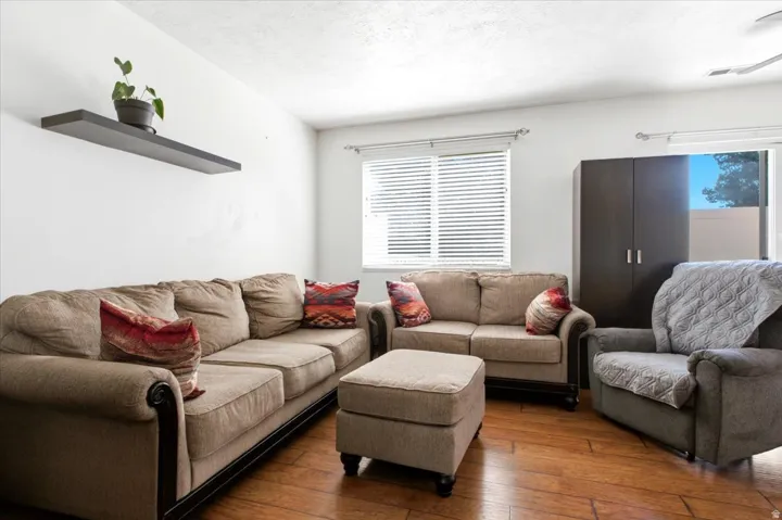Living area featuring wood-finish flooring, white walls, and a window with blinds
