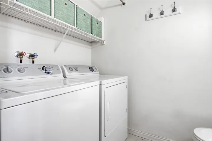 Dedicated laundry space featuring a white wire shelving unit, wall-mounted coat hooks, and durable flooring