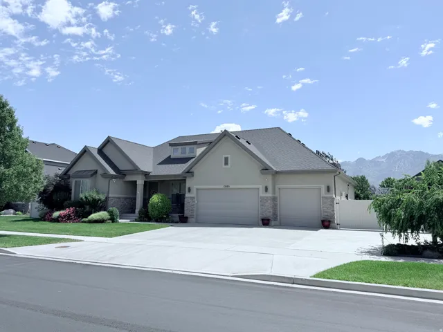 Ranch-style residence featuring a multi-gable roofline, a three-car garage, and a wide concrete driveway
