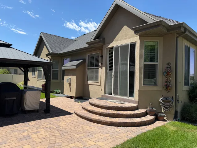 Expansive paver patio featuring a built-in gazebo structure and curved paver steps