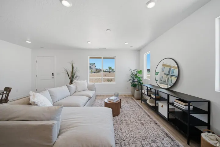 Spacious living area featuring light wood-finish flooring, recessed lighting, and large windows