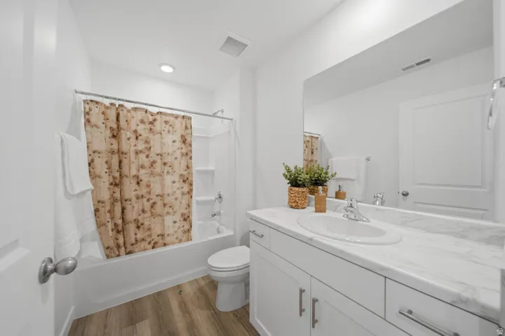 Bright bathroom featuring a white vanity with a light-toned countertop, an integrated sink, and an expansive mirror