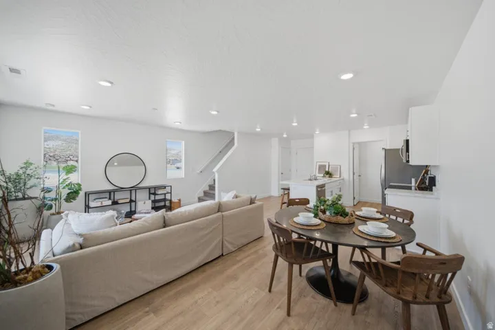 Open-concept living area featuring wood-finish flooring, recessed lighting, and a white color palette