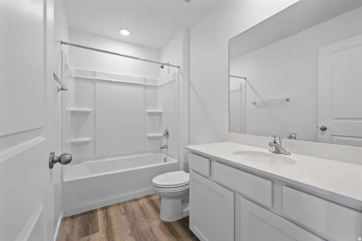 Full bathroom featuring a white vanity with integrated sink, chrome faucet, and expansive mirror