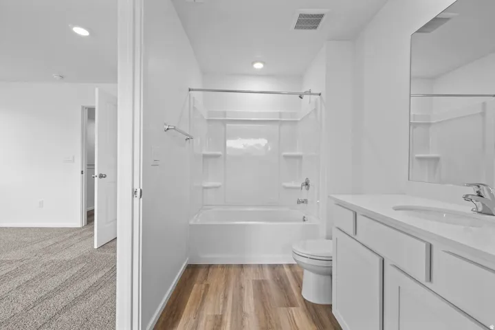 Bright bathroom featuring a white vanity with integrated sink, rectangular mirror, and a white tub/shower combination with a chrome shower rod