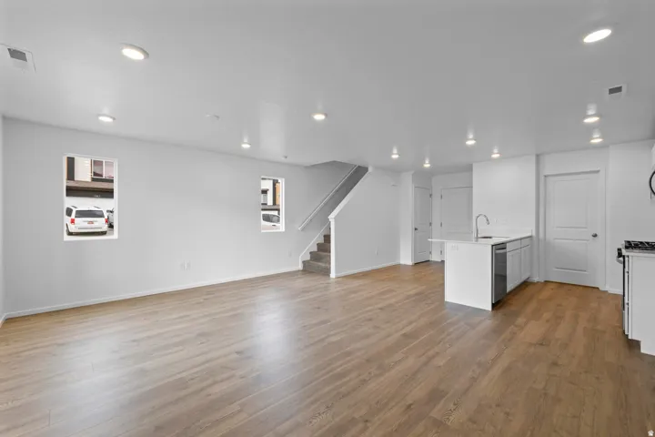 Open-concept living space featuring wood-finish flooring, recessed lighting, and white walls