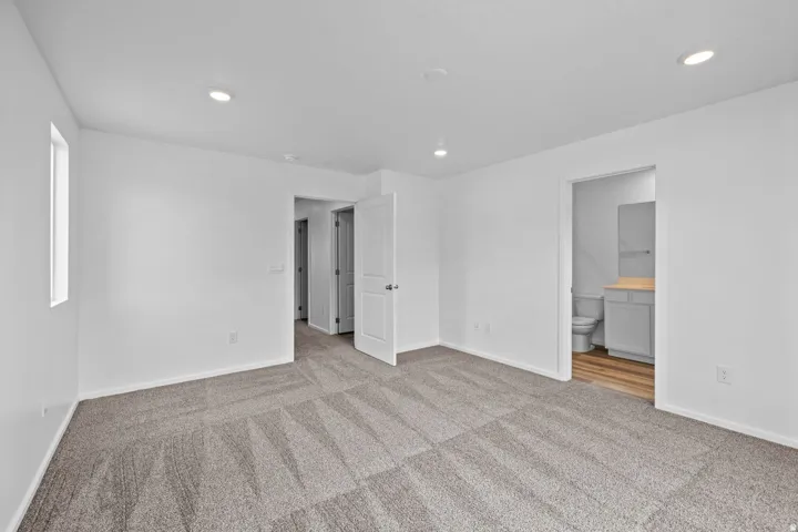 Spacious room featuring gray patterned carpeting and recessed lighting