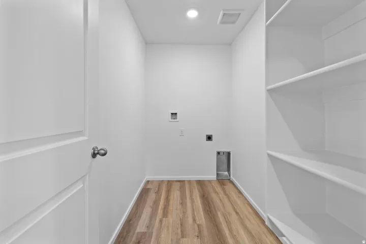 Utility room featuring wood-finish flooring, recessed lighting, white walls, and built-in shelving