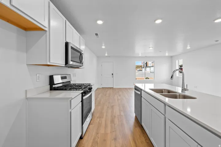 Modern kitchen featuring white cabinetry, stainless steel appliances, and wood-finish flooring