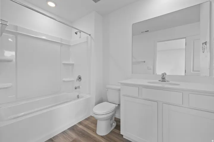 Bathroom featuring a white vanity with an integrated sink, a large wall-mounted mirror, and a white toilet