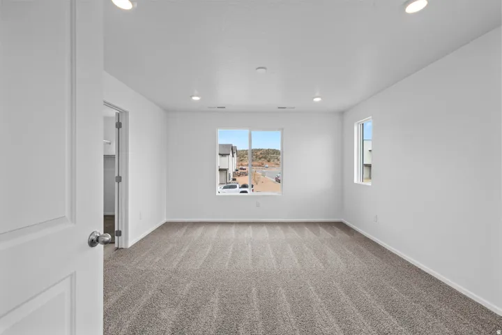Spacious room featuring neutral-toned patterned carpeting, recessed ceiling lighting, and multiple windows providing natural illumination
