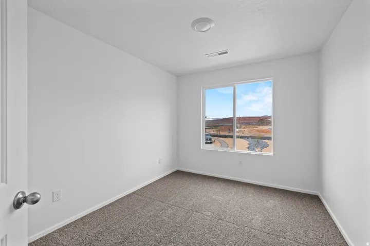 Bright interior space featuring a window with a mountain backdrop, neutral wall finishes, gray carpeting, and an overhead lighting fixture